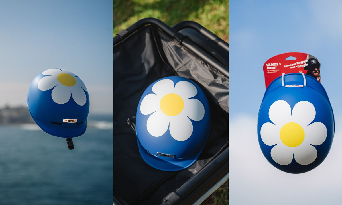 A blue Vamos Ebike Helmet featuring a large white and yellow daisy flower graphic.