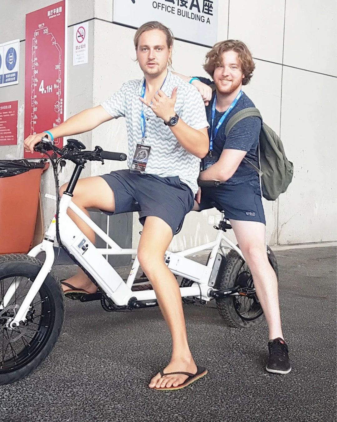 Two individuals posing with a Lectric XPedition white long-range electric cargo e-bike.