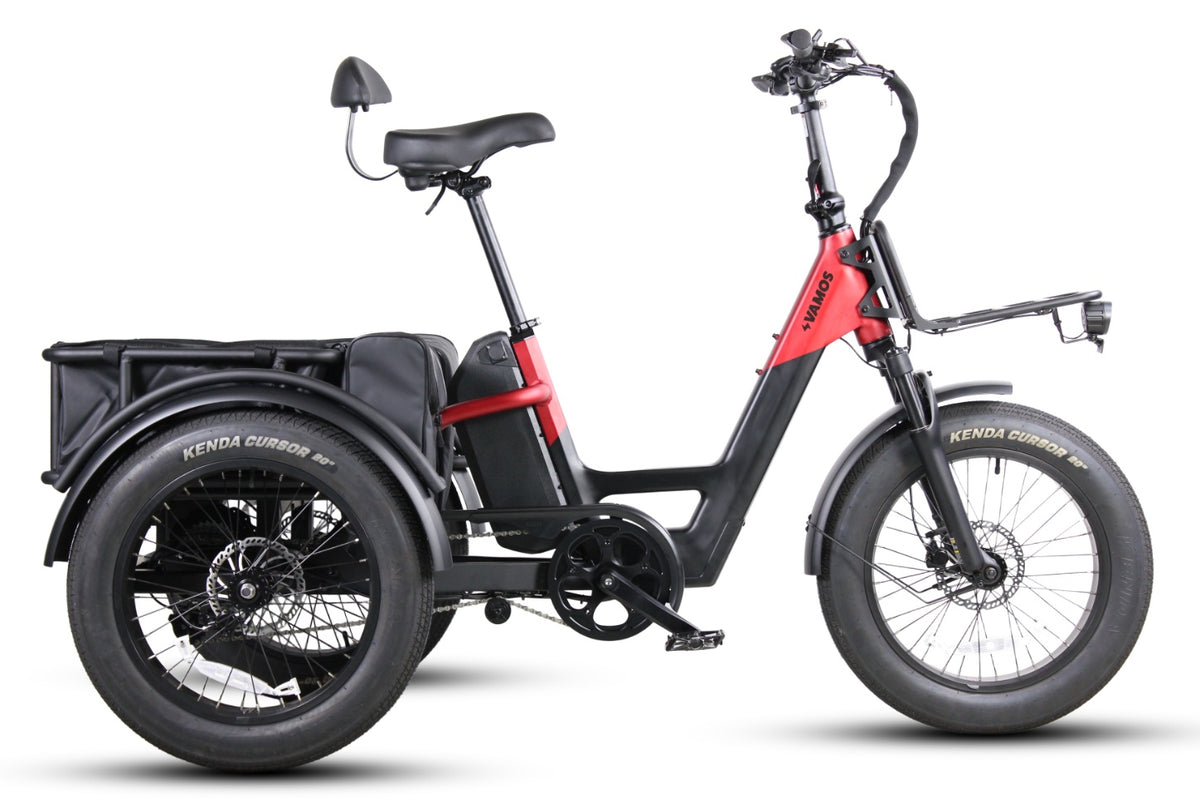 A red and black electric cargo trike with a step-through frame, a backrest saddle, and fat tires, featuring a front rack and a large rear cargo basket.