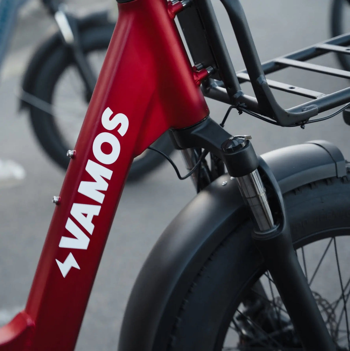 Close-up of Vamos electric bike frame and front suspension showing logo branding