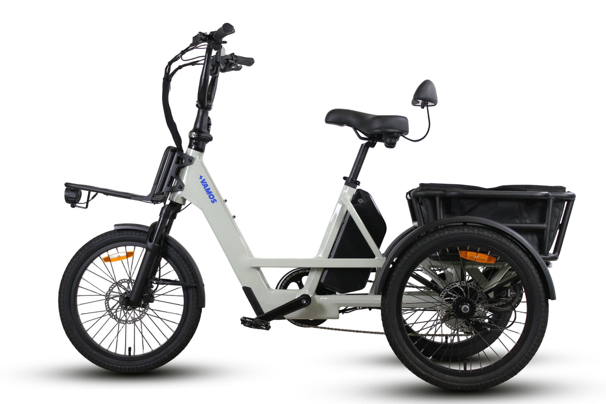 Studio product shot showing the side profile of a cream Vamos electric cargo trike featuring front and rear storage racks.