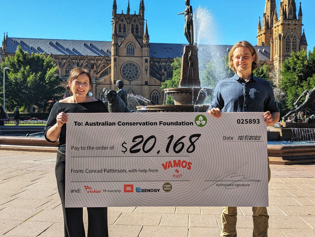 Two individuals presenting a donation check of $20,168 to the Australian Conservation Foundation