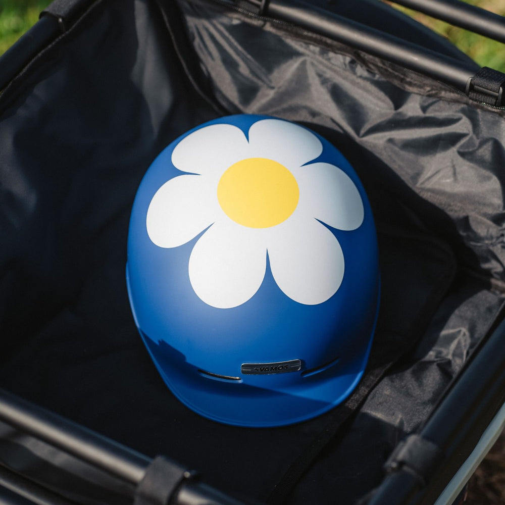 A blue vamos helmet featuring a large white and yellow daisy flower graphic on the front.