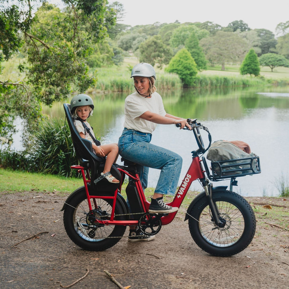 A red Vamos El Amigo all-purpose compact cargo e-bike equipped with a rear child seat.