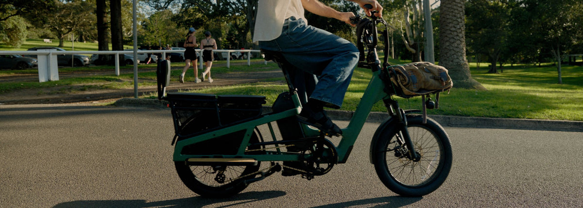 A green longtail Vamos Amigo Plus designed with a rear passenger seat and front cargo rack.
