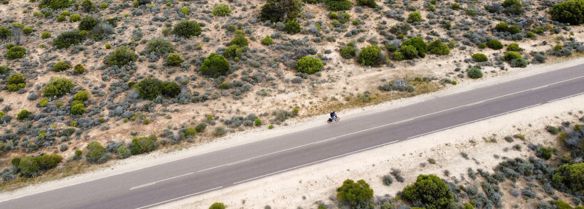 Aerial photograph captures a scenic, straight road cutting through an arid Australian outback landscape