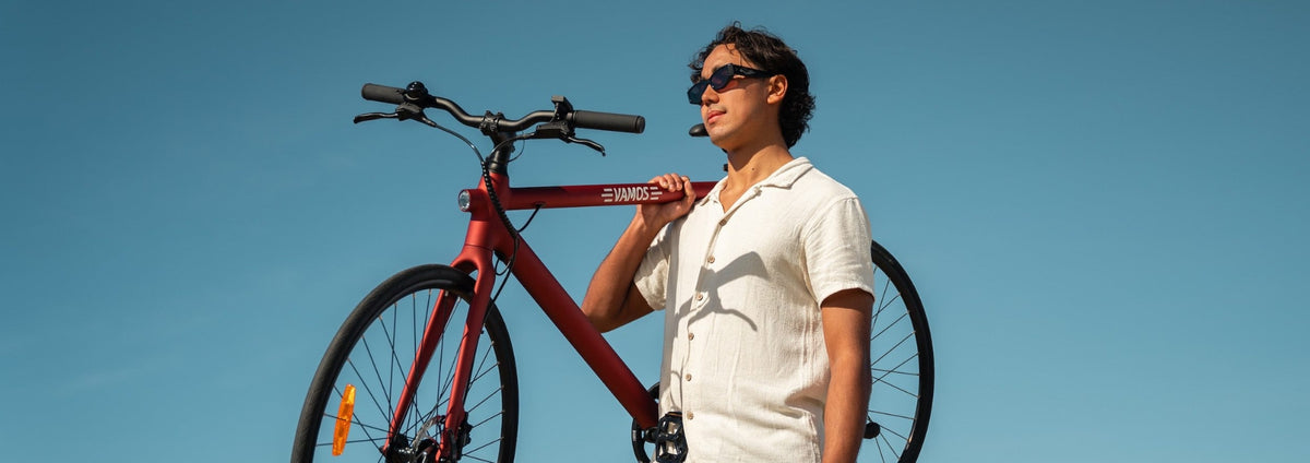 A person holding a red Vamos Pluma lightweight urban electric bike