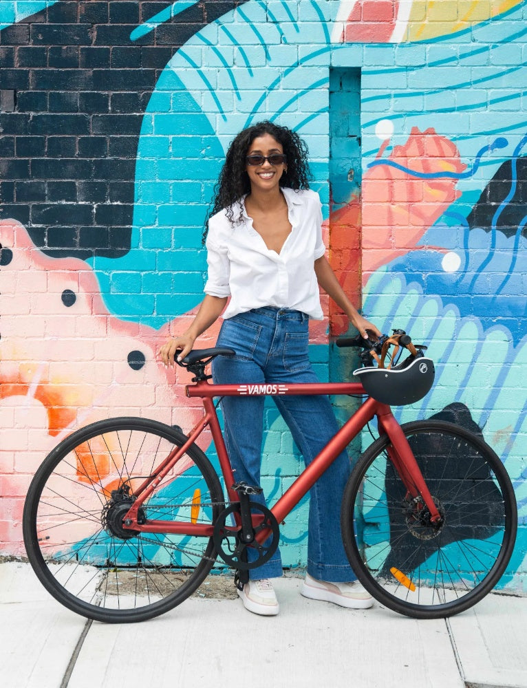 Rider standing with an electric bike in front of a colourful urban mural