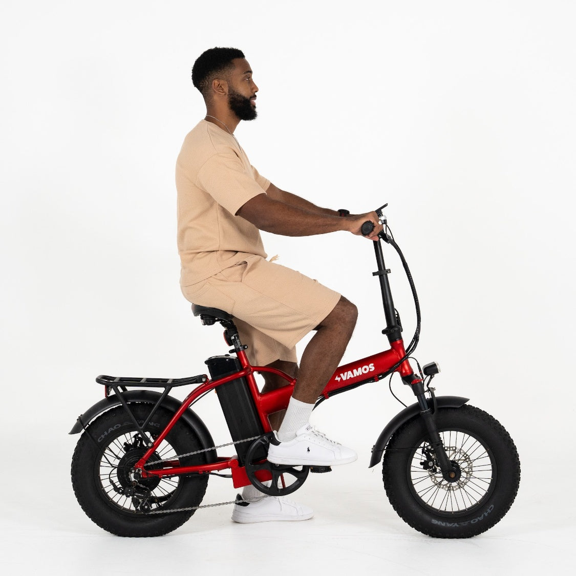 A person riding a red Vamos El Doblez folding fat-tire electric bike.