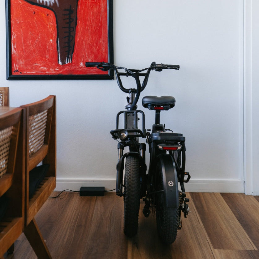 A folded El Doblez Ebike stored indoors against the wall