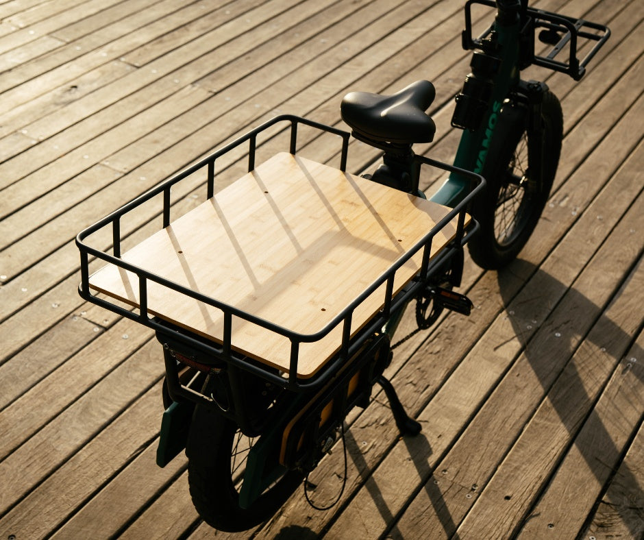 Rear cargo rack of a Vamos Amigo Plus electric commuter bike, which features a sturdy metal railing and a wooden deck.