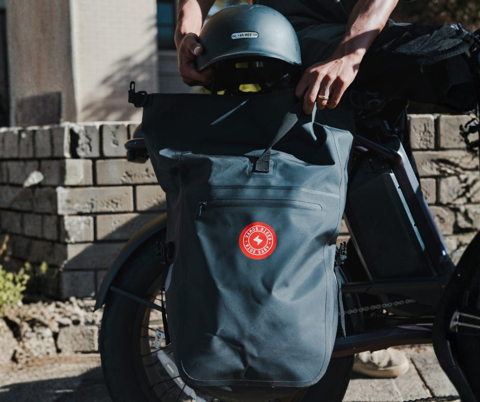 A dark gray waterproof pannier bag attached to an e-bike rack.