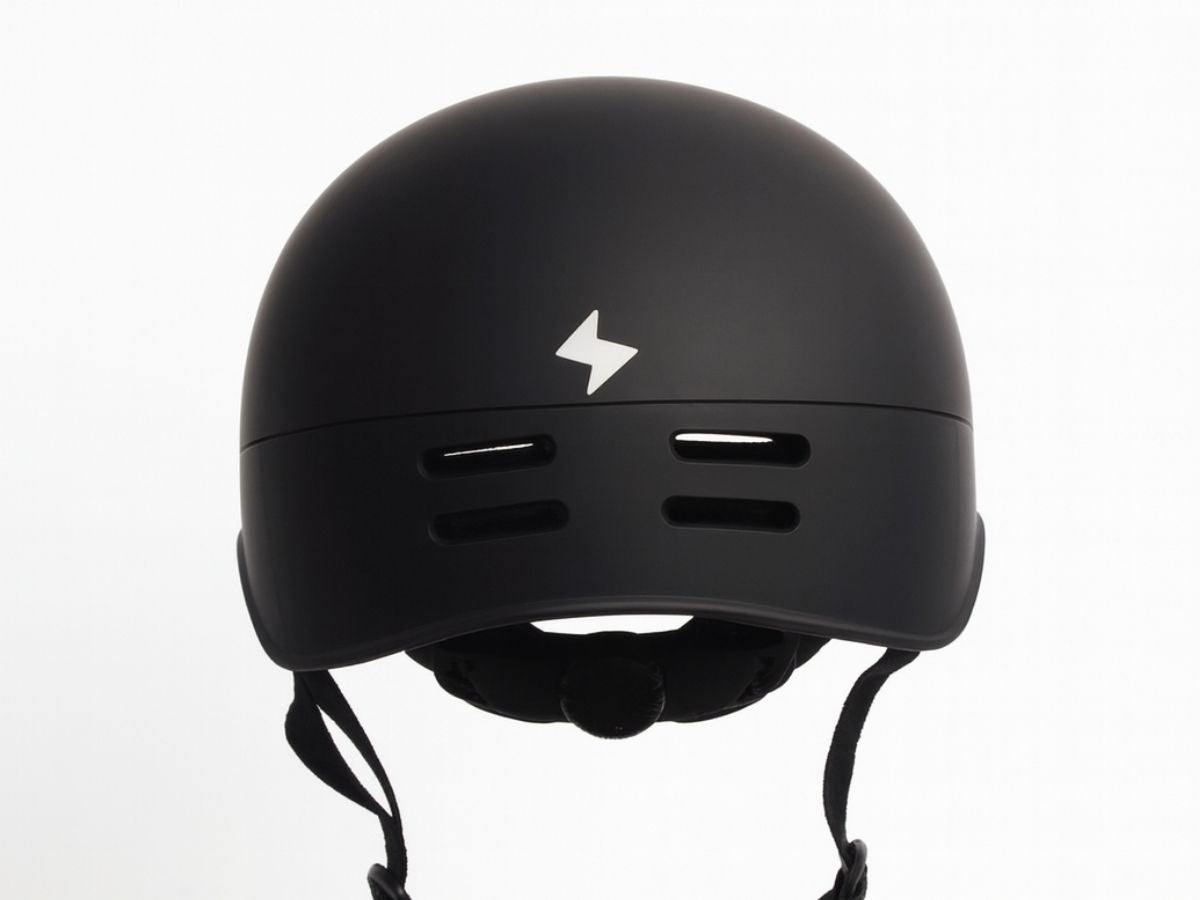 Rear view of matte black Vamos bike helmet with white lightning bolt logo and ventilation slots.
