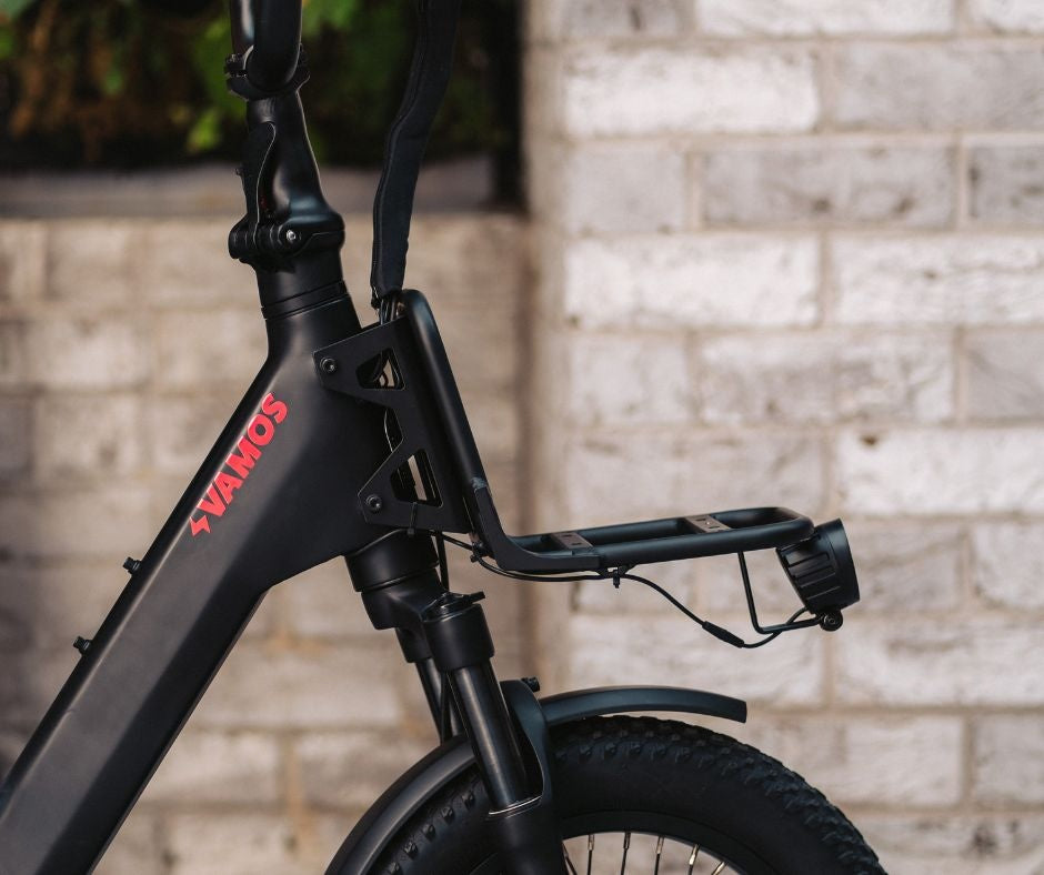 A front cargo rack installed on a matte black Vamos Doblez electric bike