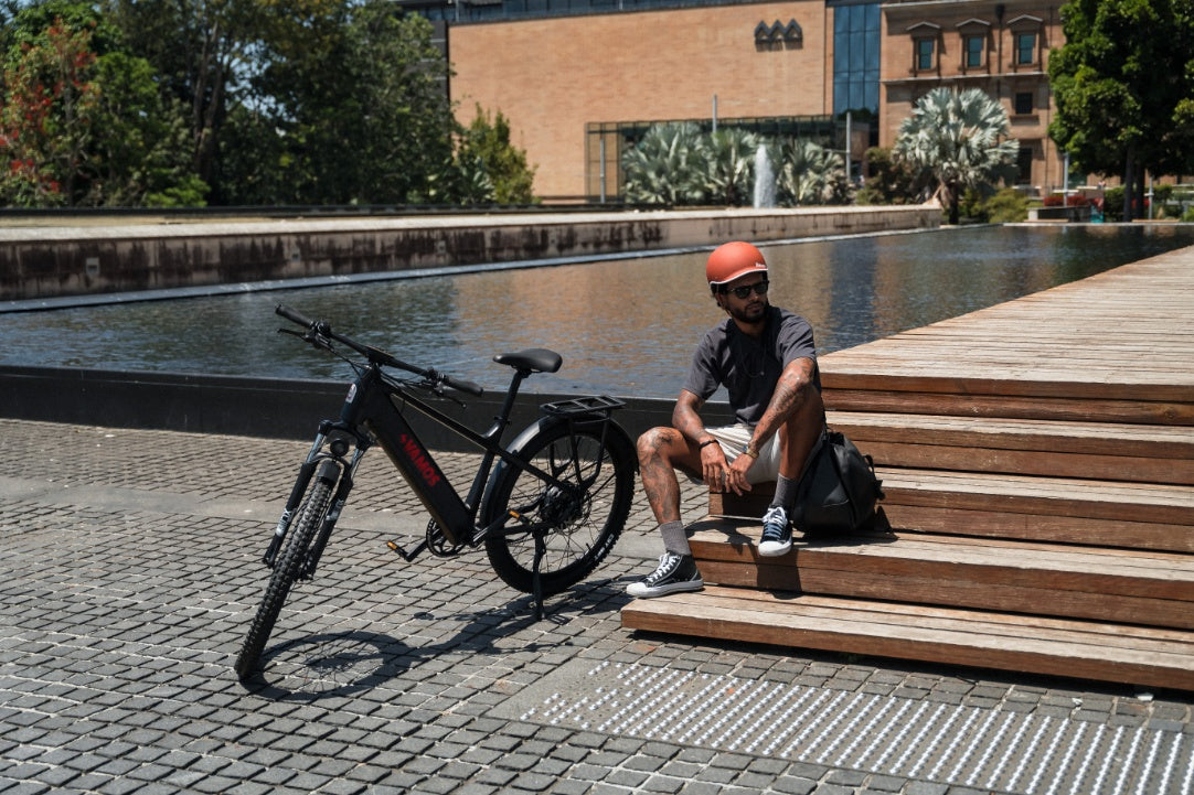 Electric bike parked beside a rider sitting on wooden steps next to an urban canal