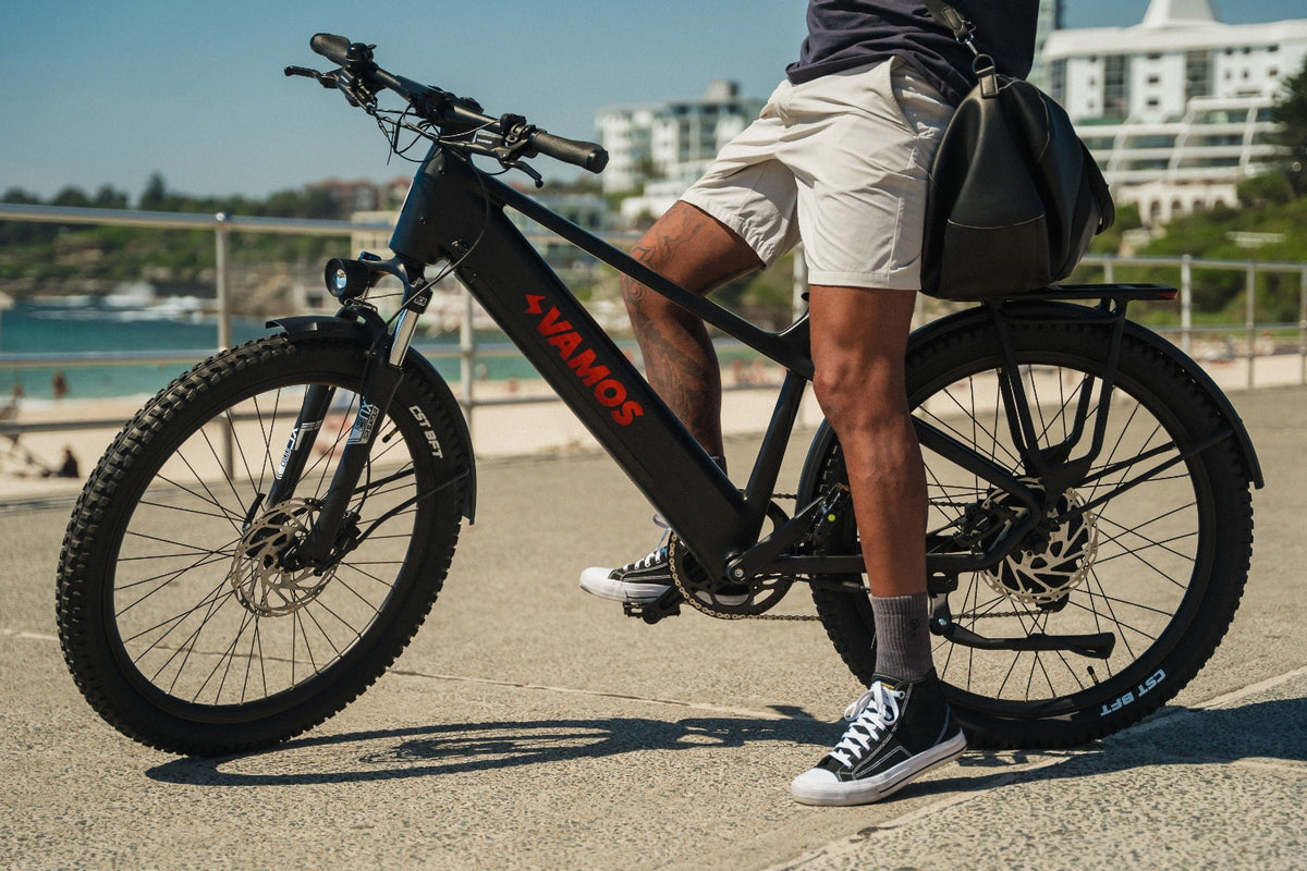 Side view of a rider standing with a fat-tyre electric bike on a beachside promenade