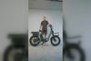 Man standing next to a grey-green Vamos electric bike in front of a white wall.