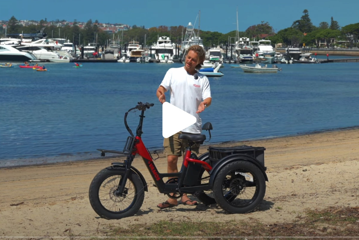 A man appears to discuss the features of red Vamos Bikes Papa Grande electric tricycle.