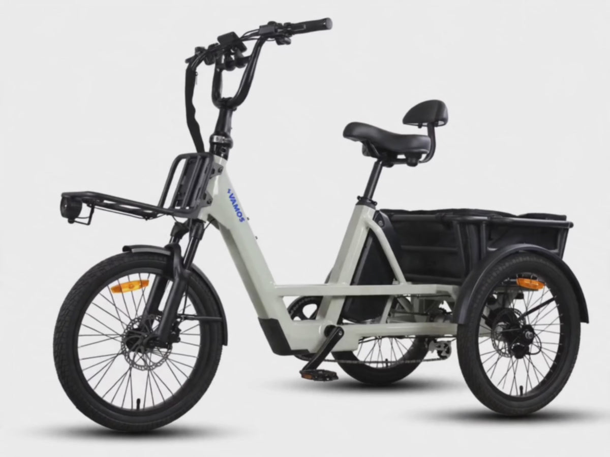 Grey Vamos electric tricycle with a front rack and rear cargo compartment set against a plain background.